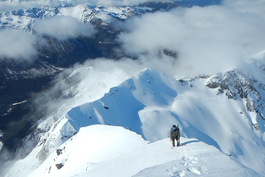 A climber summiting a snowy mountain